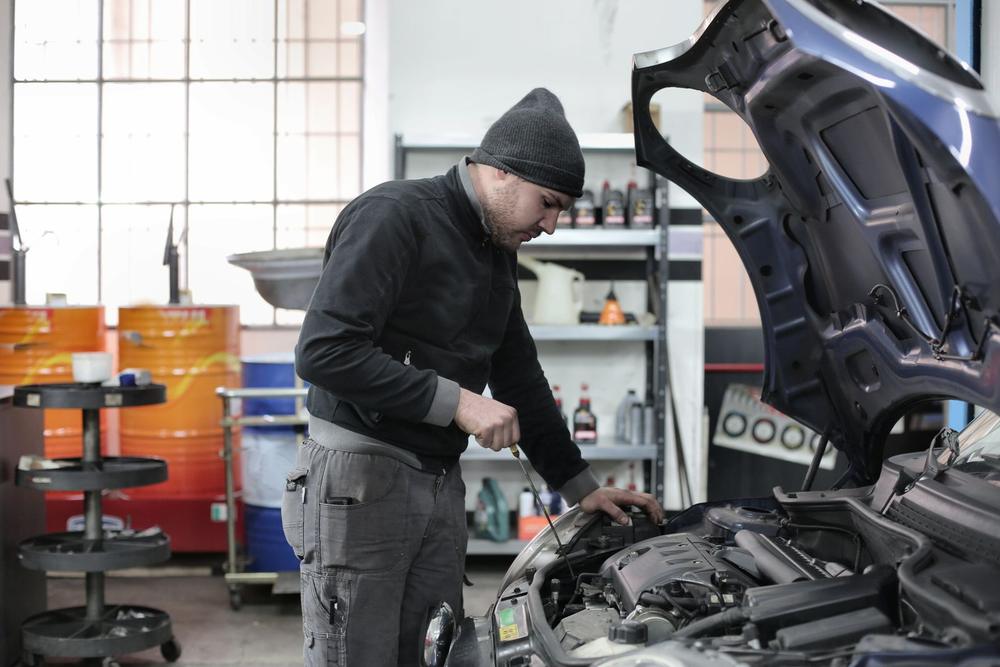 Imagem ilustrativa: mecânico trabalhando com o capô do carro aberto